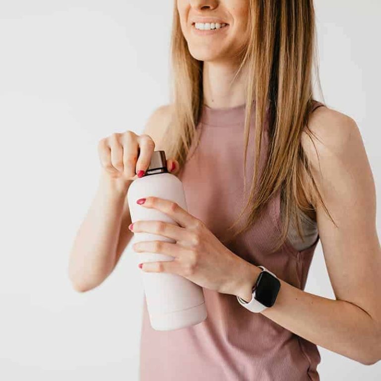 Femme souriante qui ouvre une gourde