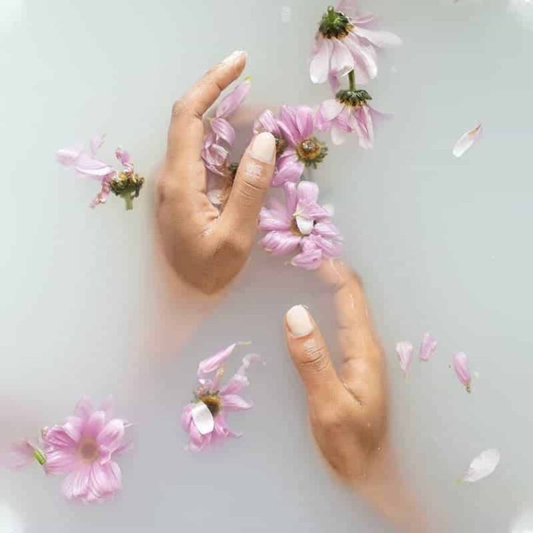 Mains posées dans un bain de fleurs roses