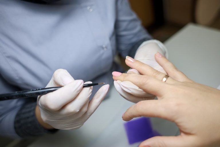 Esthéticienne réalisant une manucure simple avec limage, cuticules et pose de vernis classique