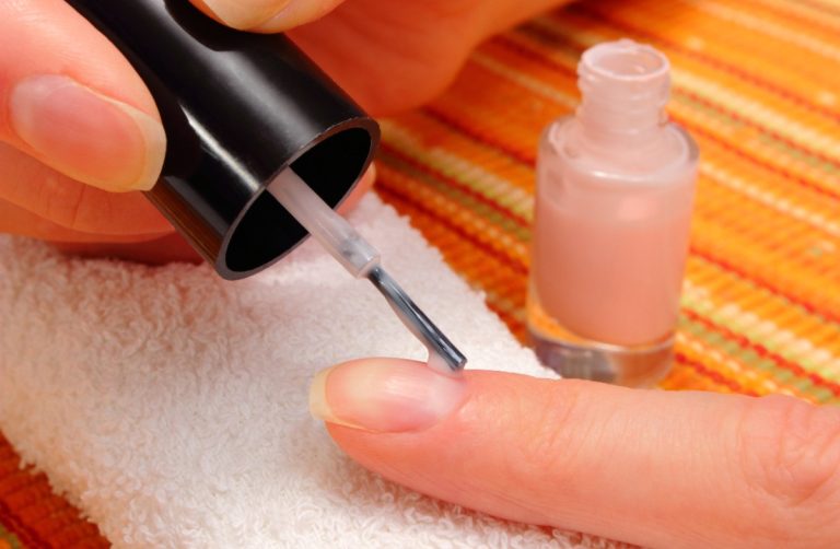 Une personne appliquant un top coat sur un vernis classique