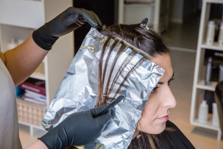 Une femme au coiffure, faisant une coloration de cheveux en rattrapant des mèches trop claires