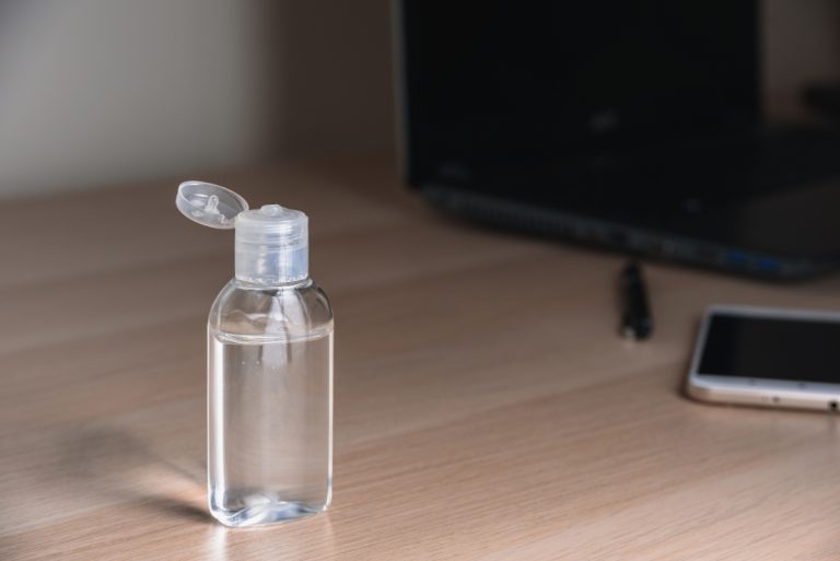 Un flacon d'alcool à friction déposé sur la table dans un bureau