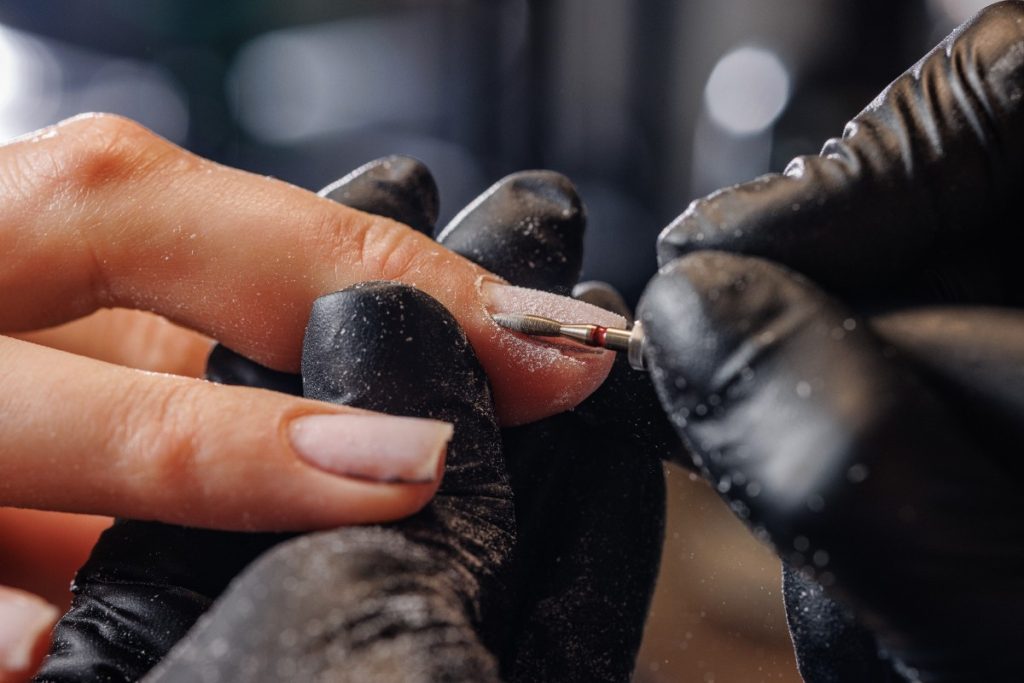 Une esthéticienne qui répare un ongle cassé