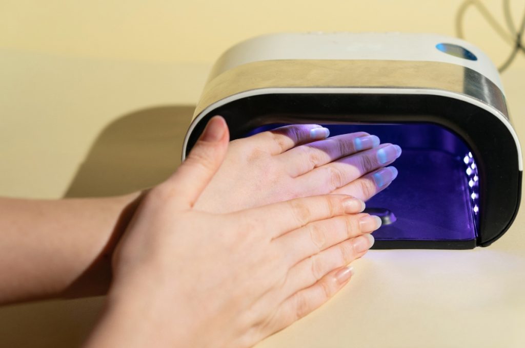 Une femme mettant ses mains sous une lampe UV