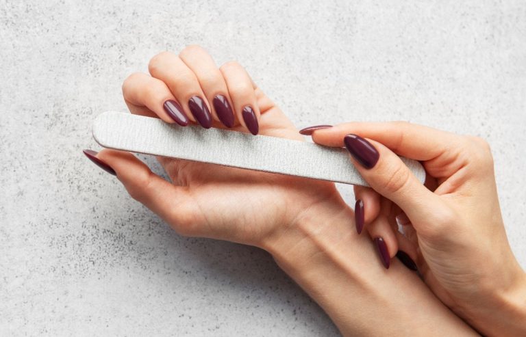 Une femme qui lime ses ongles avec du vernis semi-permanent