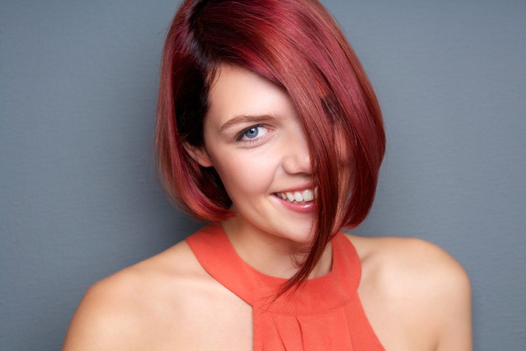 Une femme souriante avec des cheveux asymétriques colorés