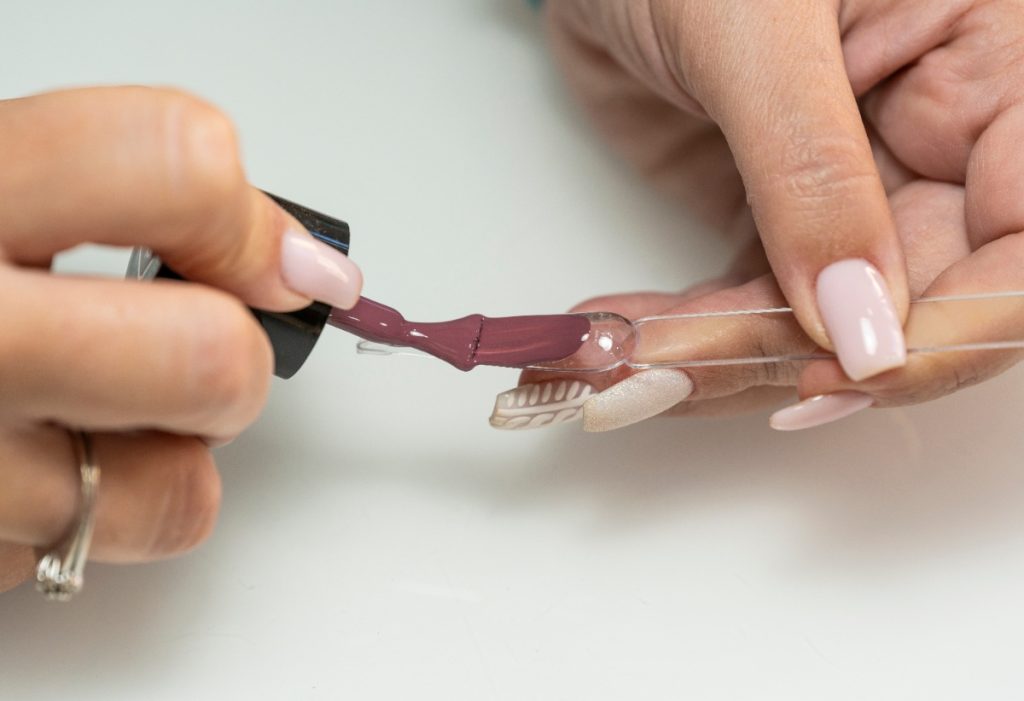 Une femme appliquant du vernis sur du faux ongle