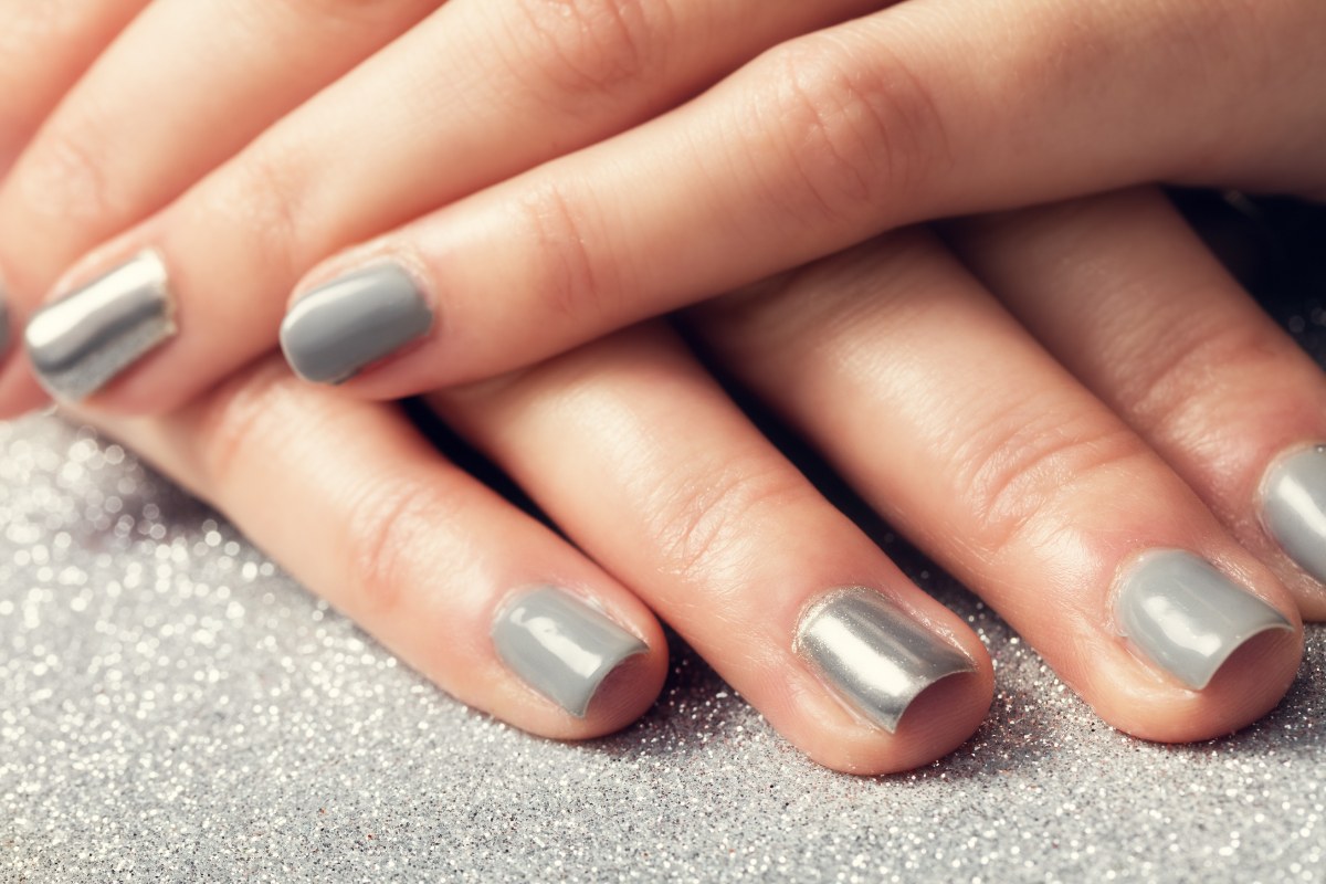 Mains d'une femme avec des vernis gris clair