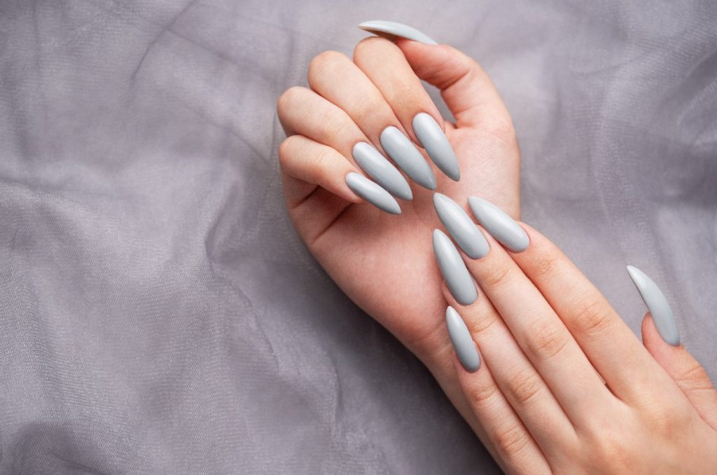 Mains avec des ongles gris sur fond dentelle grise