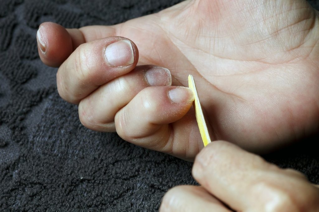 Une personne qui lime un ongle avant d'enlever une écharde