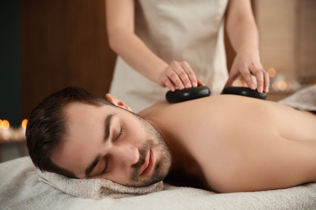 Un bel homme recevant un massage aux pierres chaudes 