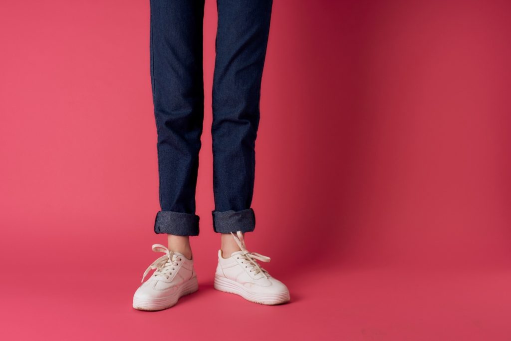Une femme portant un pantalon bleu marine et un basket blanc