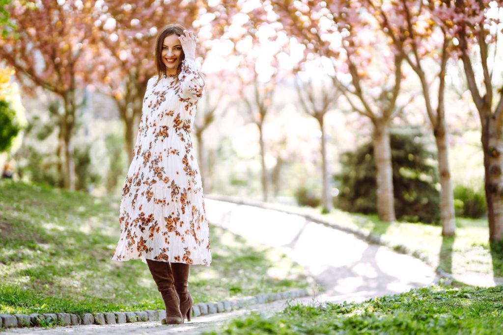 Une femme marchant dans un par avec une robe fleurie et une botte marron