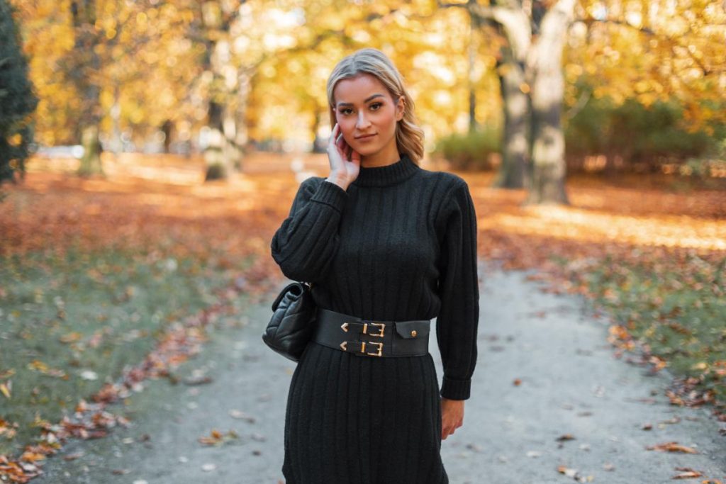 Une femme portant une robe pull noire avec une ceinture