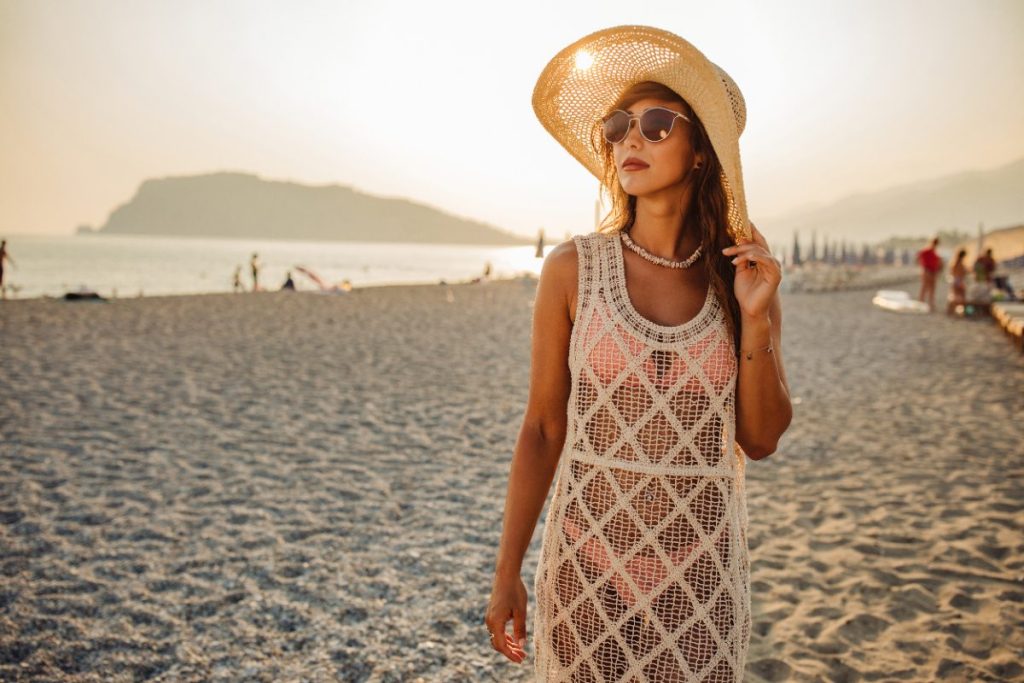 Une femme portant une robe transparente avec un chapeau à la plage