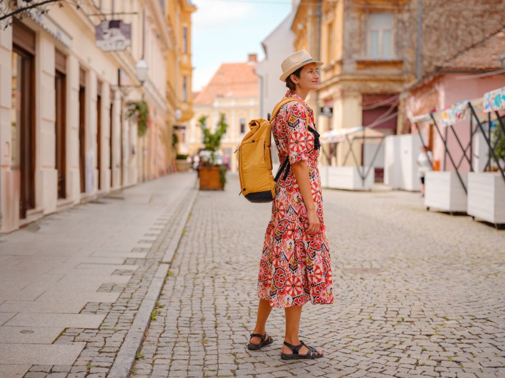 Une femme portant une roble fleurie avec un sac à dos et une sandale