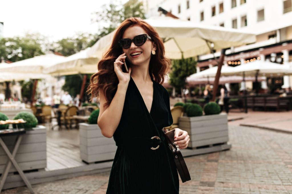 Une femme souriante au téléphone avec une robe et une lunette noire
