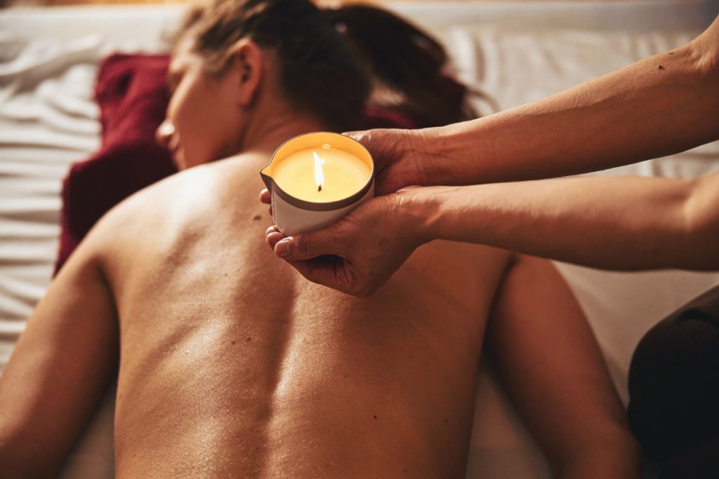 Mains tenant une bougie de massage sur le dos d'une femme
