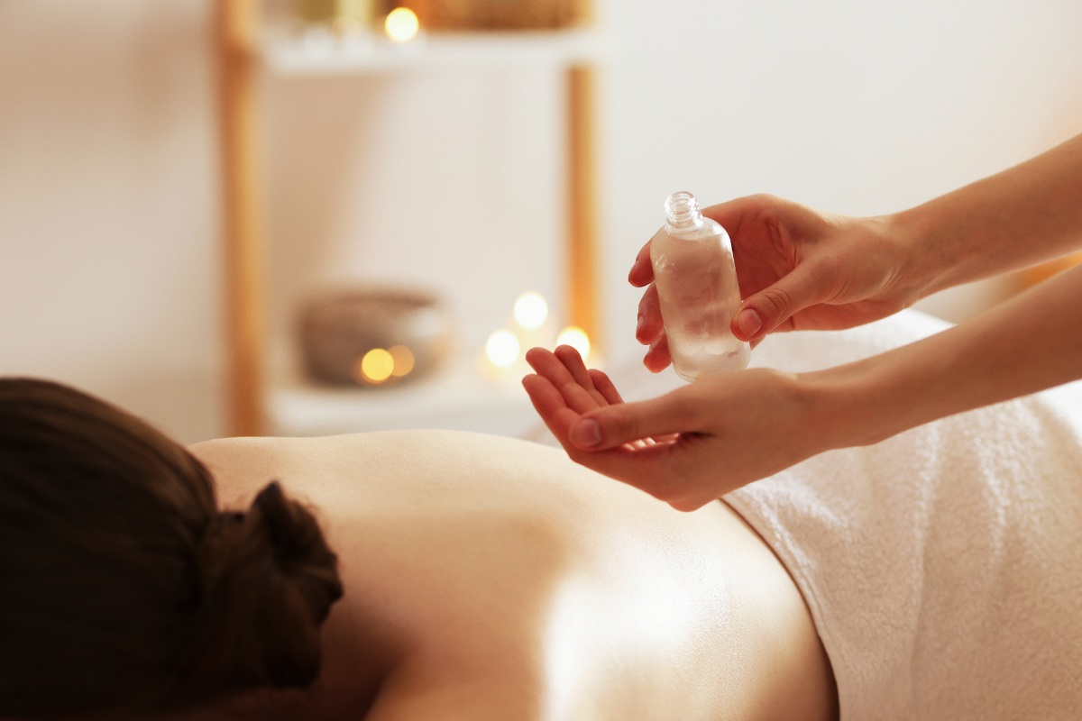 Une personne faisant un massage de dos pour une femme avec de l'huile essentielle
