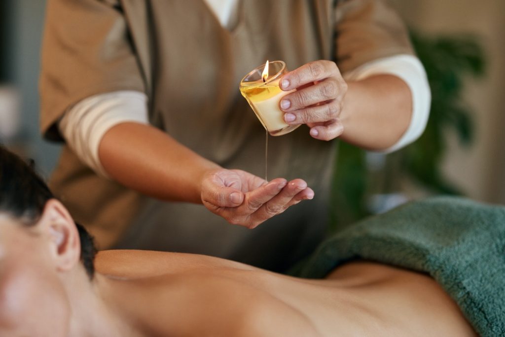 Une personne faisant un massage de dos pour une femme avec une bougie
