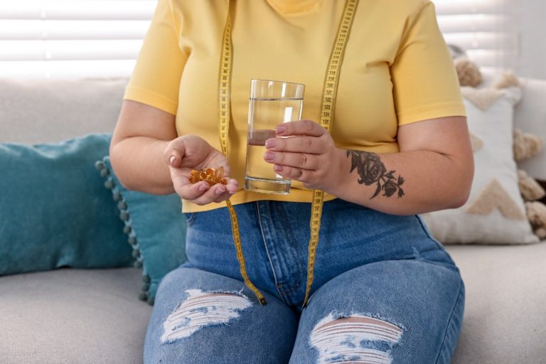 Une femme assise sur un canapé et prend du complément alimentaire
