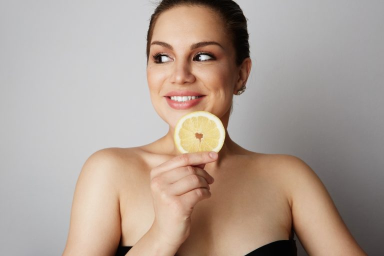 Une femme souriante tenant une tranche de citron