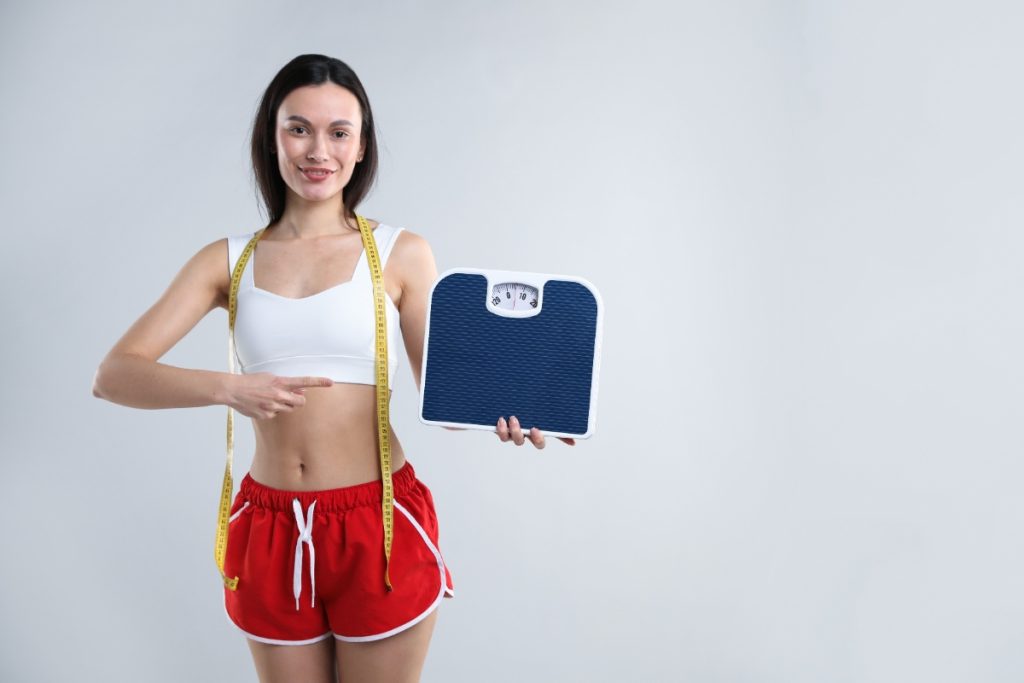 Une jeune femme en forme tenant une balance et un ruban jaune