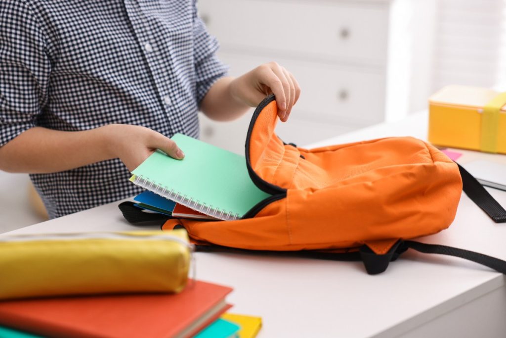 Un étudiant rangeant des cahiers dans un sac