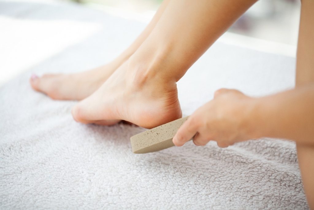 Une personne faisant des soins de pieds avec une pierre ponceuse
