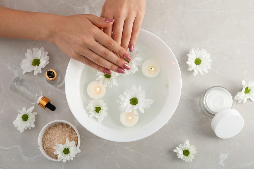 Bol de bain pour les mains, sel de bain, fleurs blanches, bougies et pots de crème