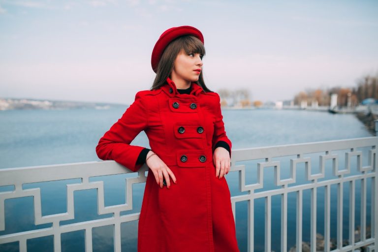 Une femme aubord d'un lac avec un manteau rouge