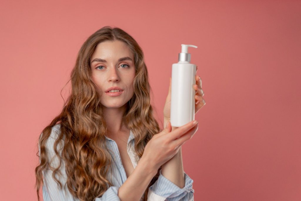 Une femme aux longs cheveux tenant un flacon de shampoing