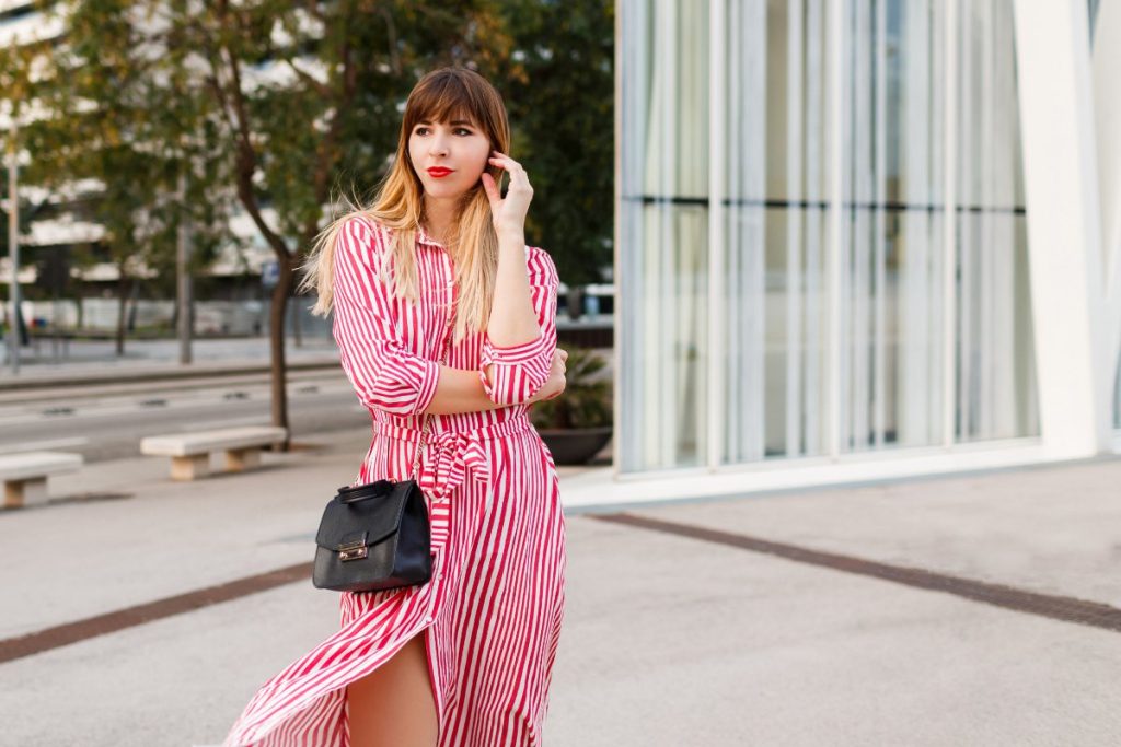 Une femme stylée avec une robe rayée et un sac noir