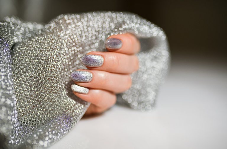 Main avec des vernis à ongles argentés