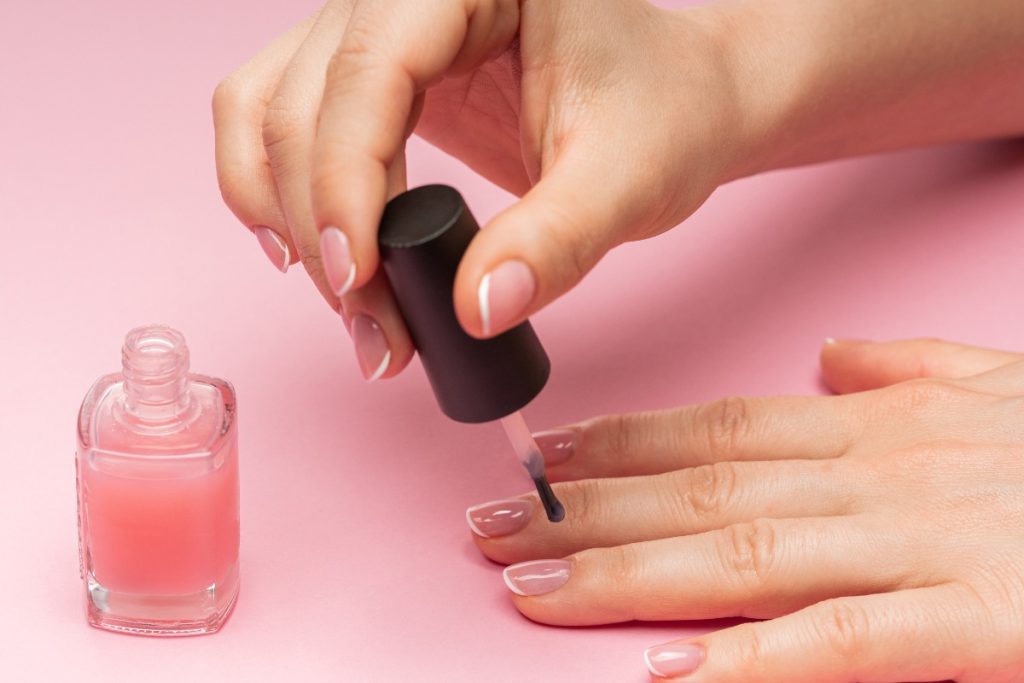 Mains réalisant une manucure avec un durcisseur à ongle